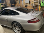 Silver Porsche 996 with BetterBodies Motorsport full aero kit, including front lip, side rockers, ducktail, and rear diffuser.