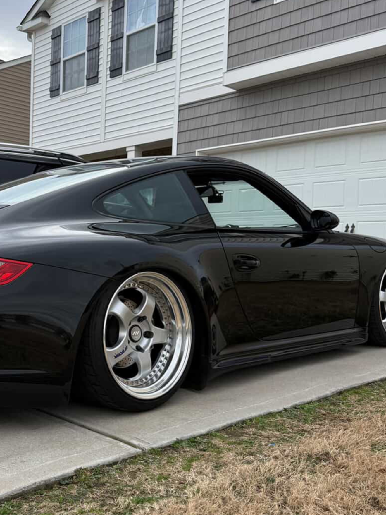 Fiberglass Porsche 997 Mach II side skirts for Carrera/GT3 narrow body, installed on a black car with BetterBodies Motorsport branding